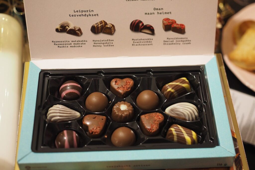 Geöffnete Pralinenschachtel mit verschiedenen Pralinen auf einem festlich gedeckten Tisch