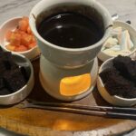 Schokoladenfondue mit Früchten, Brownies und Marshmallows in Schälchen