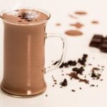 Glas mit heißer Schokolade neben einer angebrochenen Tafel dunkler Schokolade