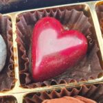 Glänzende rote Herzpraline in einer Pralinenschachtel