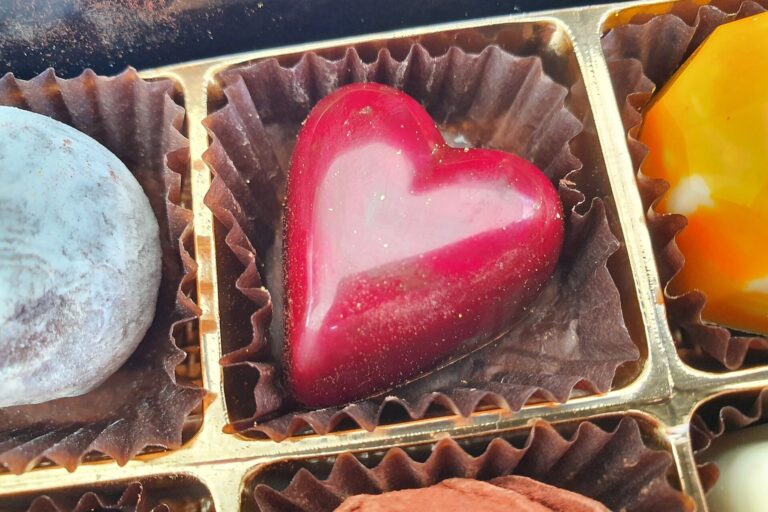 Glänzende rote Herzpraline in einer Pralinenschachtel